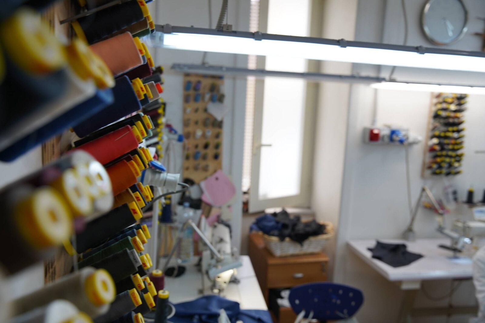 Laboratorio Sartoria Trinchese con rocchetti di filo e postazioni di lavoro